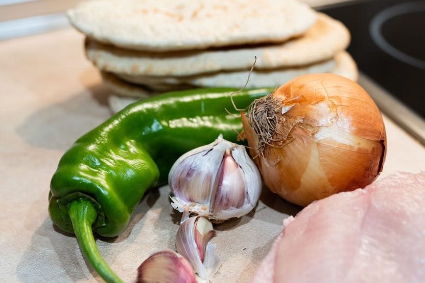 fresh vegetables with pita bread and chicken fillet placed on table in kitchen
